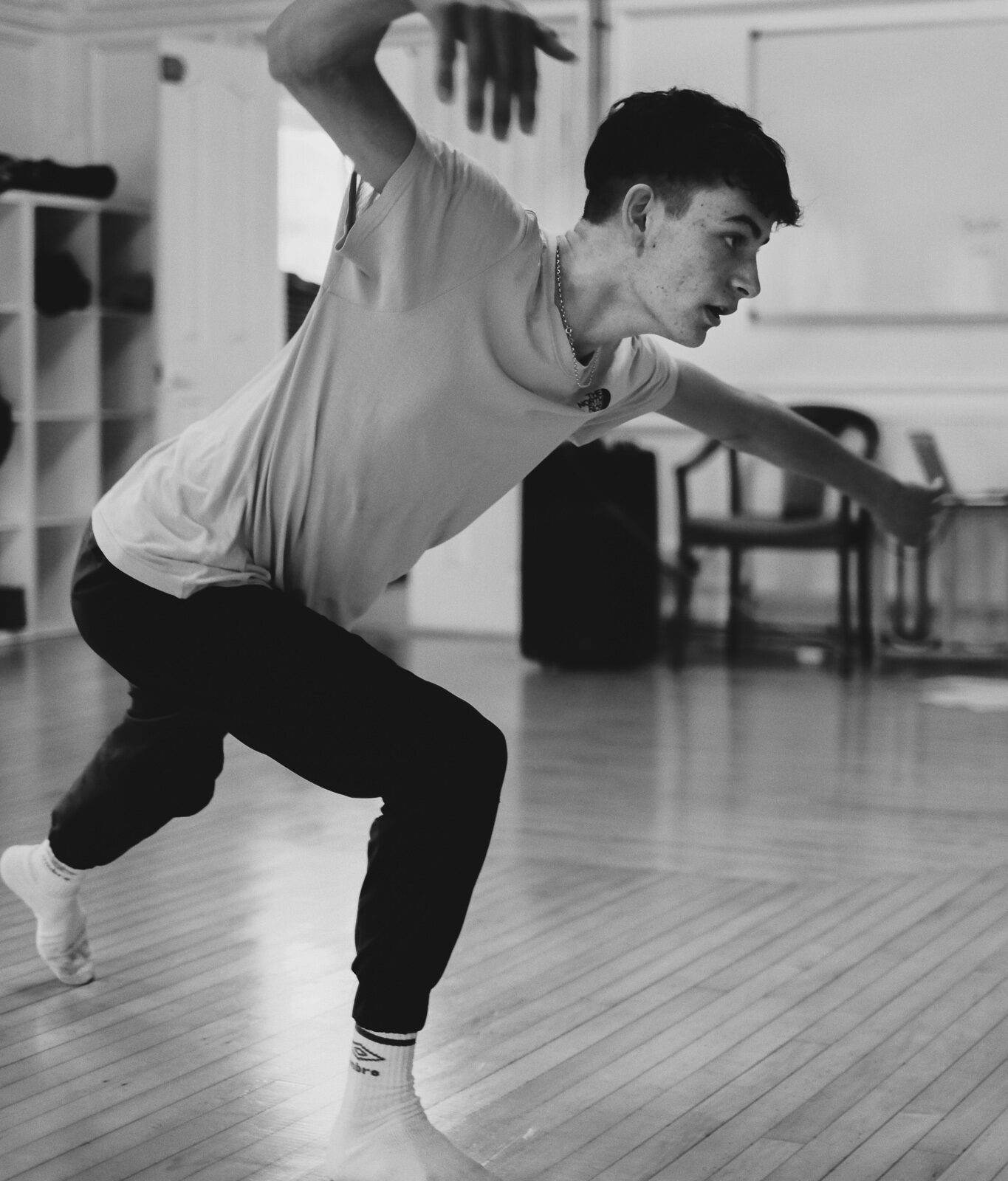 A teenage boy lunges forward during a dance rehearsal