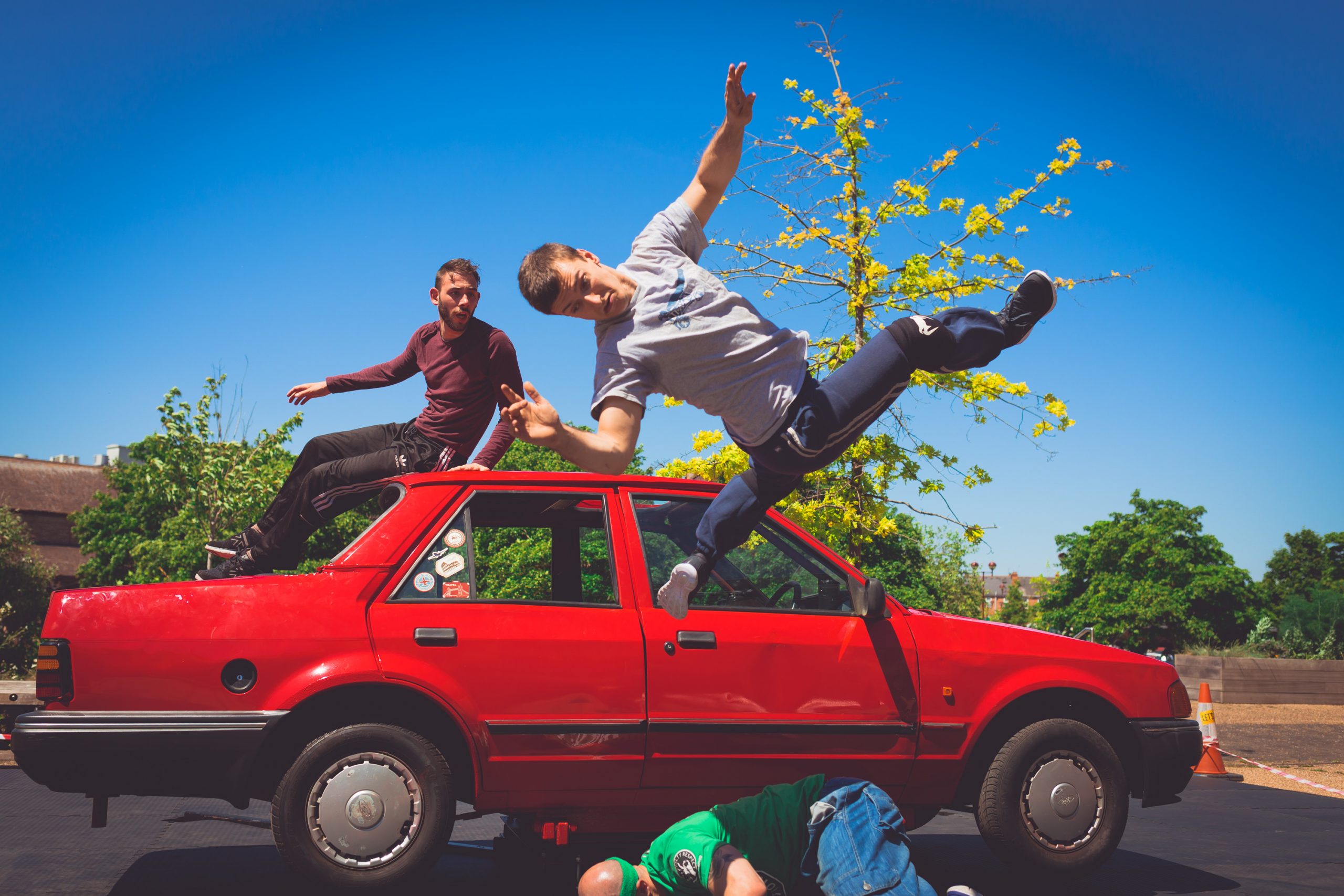 Dancing in mid-air jumping off the side of a red car